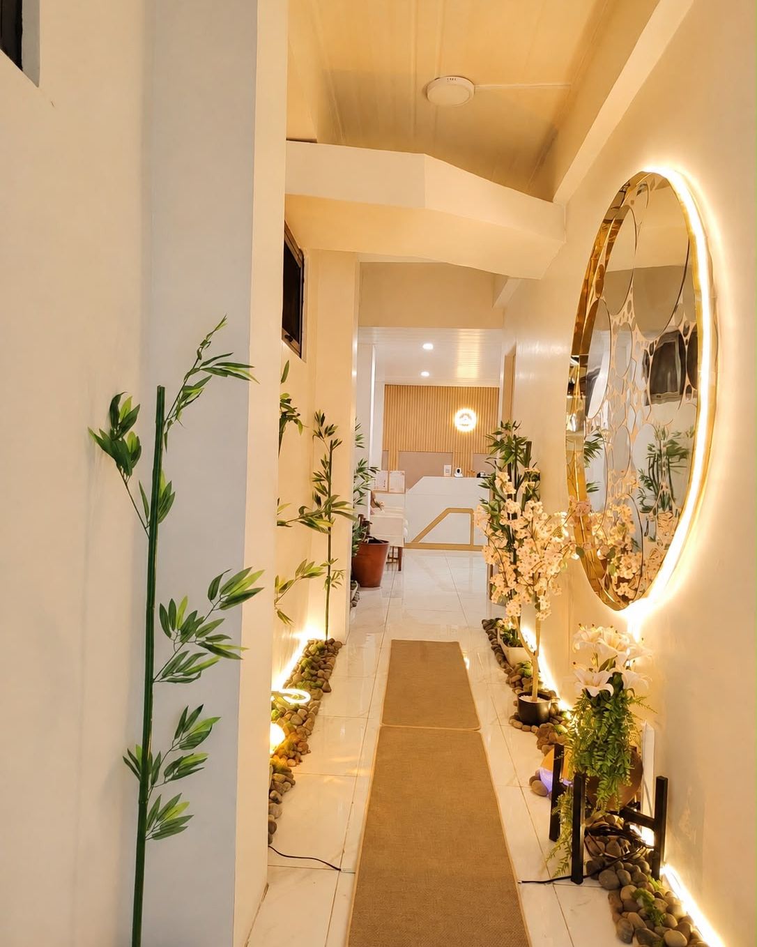 Entrance hallway of Hikari Massage and Spa in La Trinidad, with bamboo, cherry blossoms, river stones and a round backlit mirror