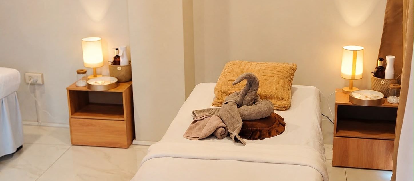 Massage bed at Hikari Massage and Spa with fresh white linens, a folded towel swan and warm bedside lamps